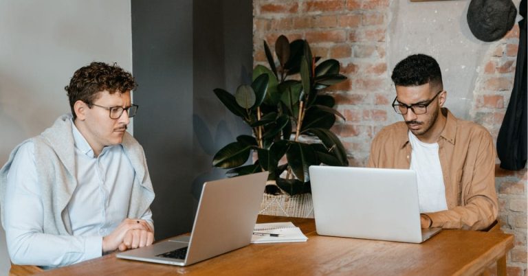 Two men working on laptops in an office setting, representing career development and recruitment services for job seekers