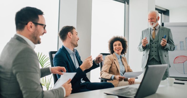 Group coworkers smiling during a business meeting, representing teamwork and benefits of investing in labour hire services